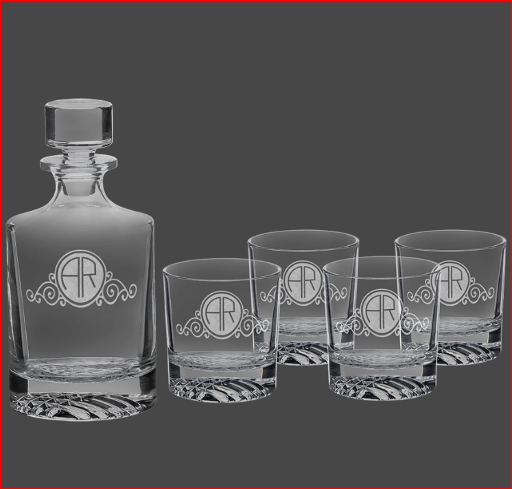 Set of crystal decanter and glasses with monogram design on a dark background